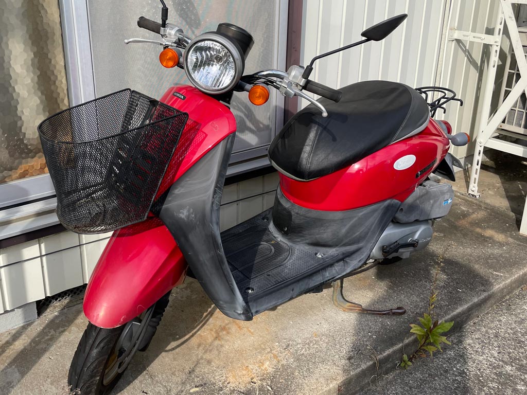 【不用品回収・買取フォーカス】遺品処分に伴い買取したホンダ・トゥデイ(原付スクーター、赤)。石巻市のアパート駐輪スペースにて撮影。
